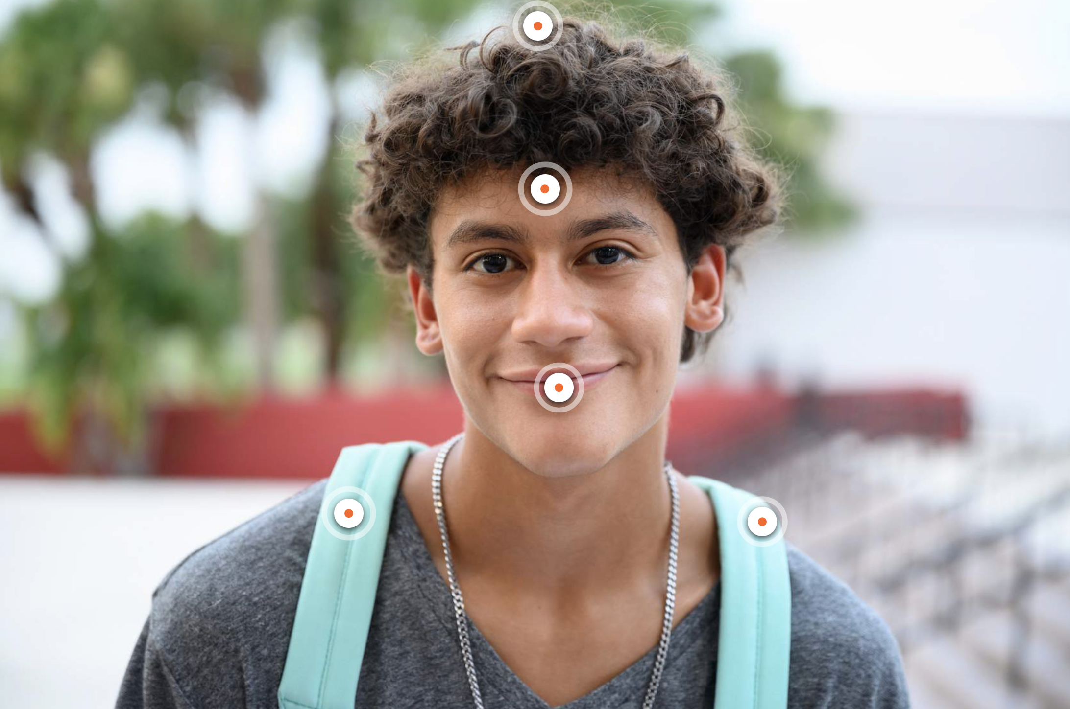 Smiling teen with interactive target icons on their face and shoulders.