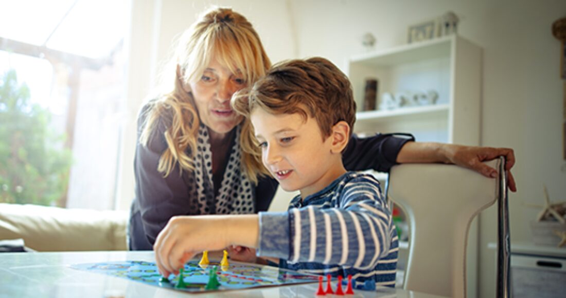 A foster parent plays a board game with a child in foster care.