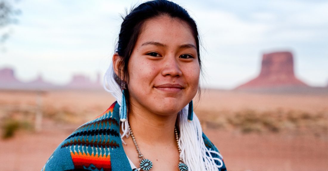 Young woman of native american heritage stands outside.