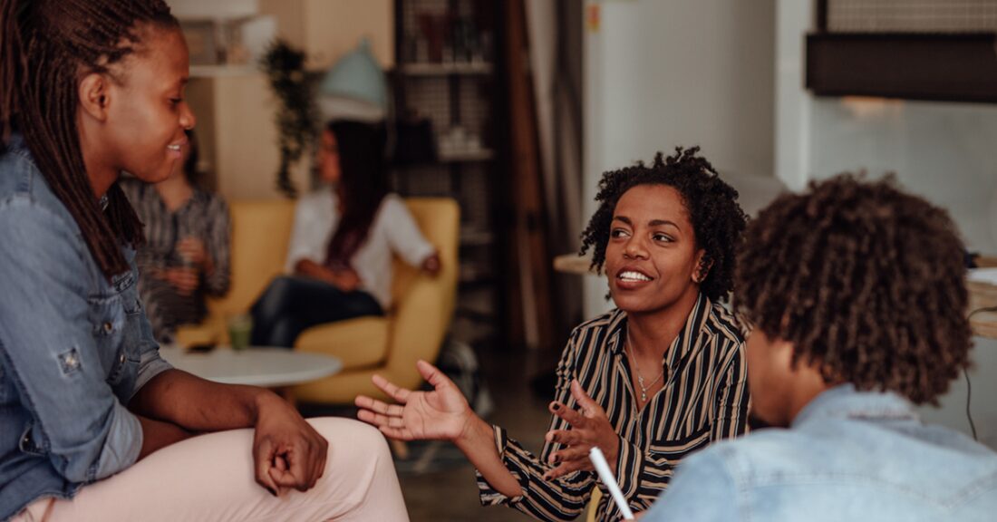 A young woman listens as an older woman counsels her and another young person.