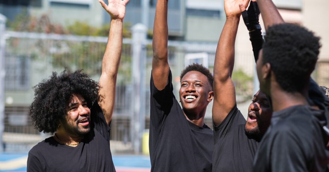 A group of young black men in the act of giving each other a high five.