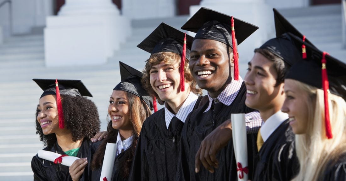 A diverse group of high school students post-graduation, wearing caps and gowns and holding diplomas.