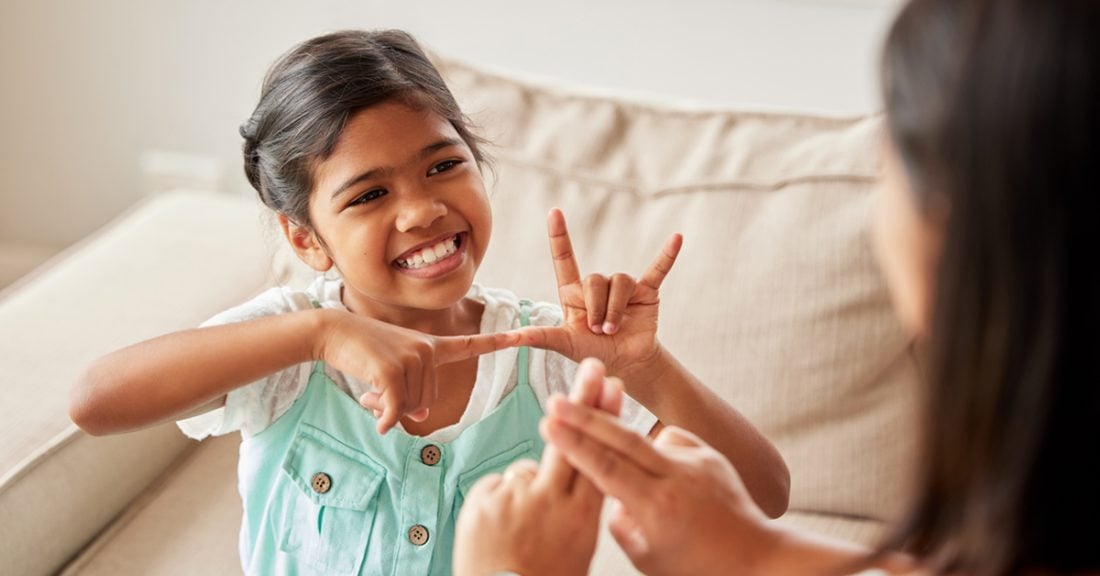 A young girl of color communicates using sign language