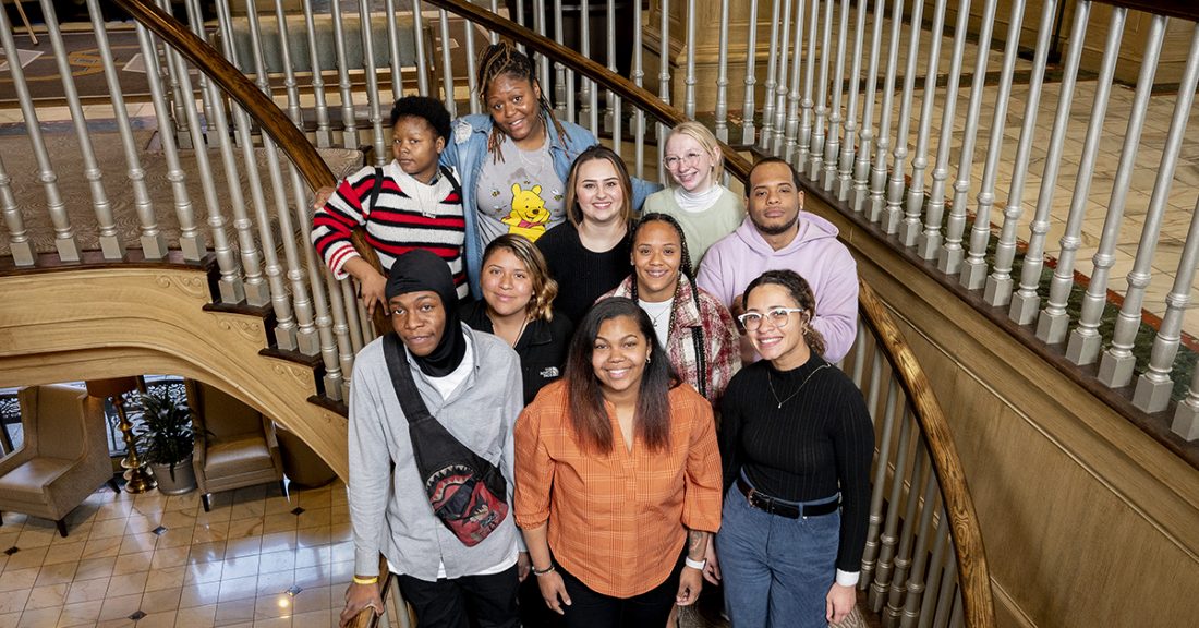 Young adults, all 2023 LEAP fellows, pose on a staircase, smiling at the camera.