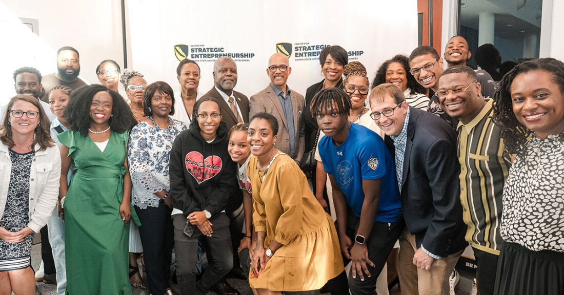 A diverse group of professionals gather for a photo in front of a banner that reads, “Center for Strategic Entrepreneurship.”