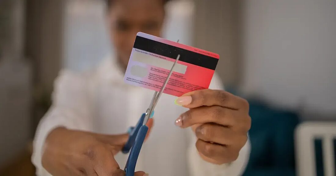 A closeup image of a scissors cutting through a credit card.