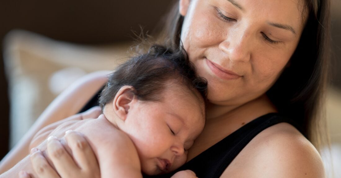 A native american mother cradles her newborn baby to her chest.