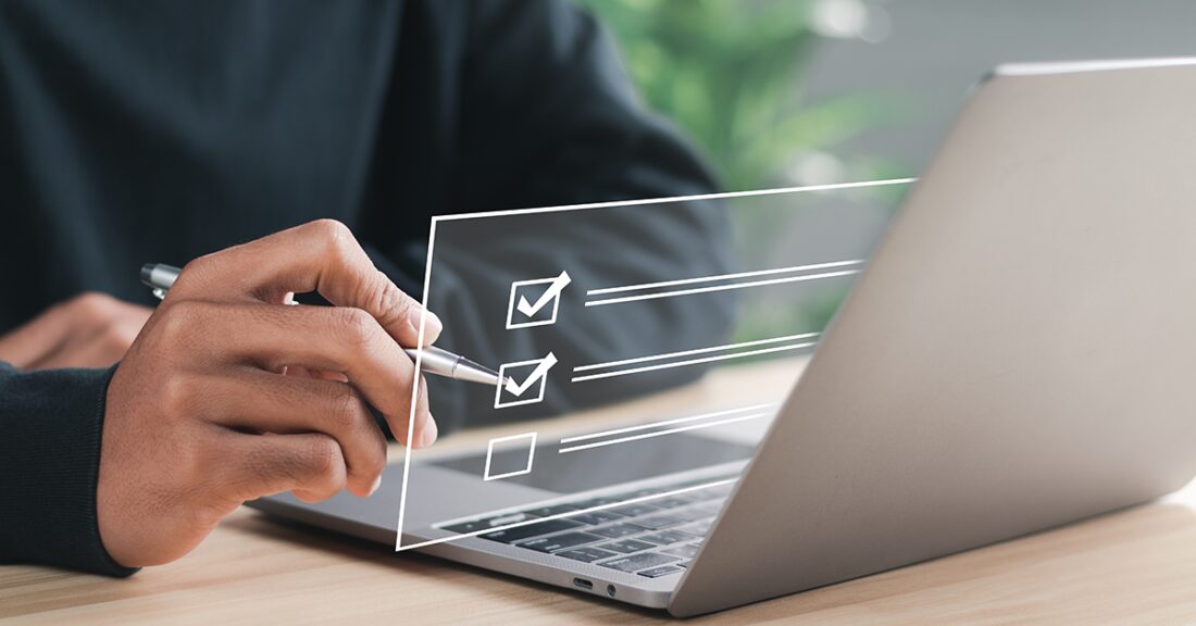 Person holding a pen next to a laptop, with a digital checklist overlay on the screen.