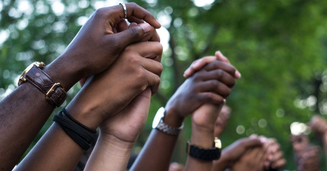 A close-up of the hands of many colors linked in solidarity.