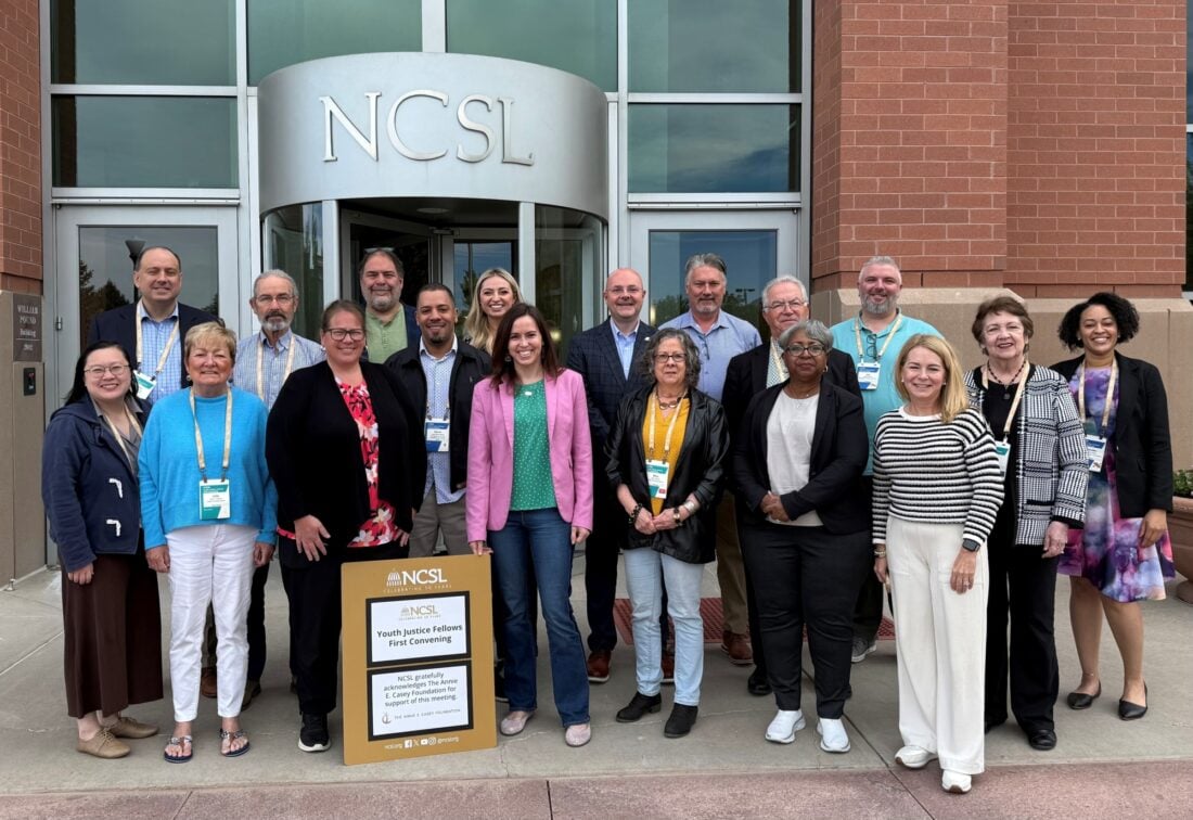 18 lawmakers pose, smiling, during the first-ever convening of the Youth Justice Fellowship.