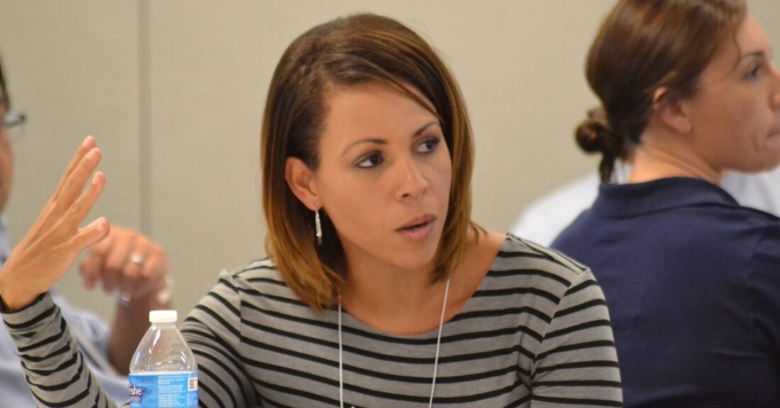 Woman with shoulder-length hair in a meeting of professionals