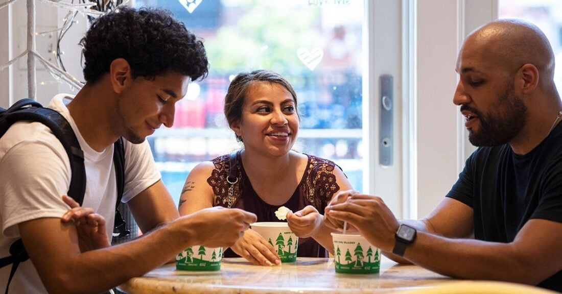 Teens at a table share ice cream with an adult