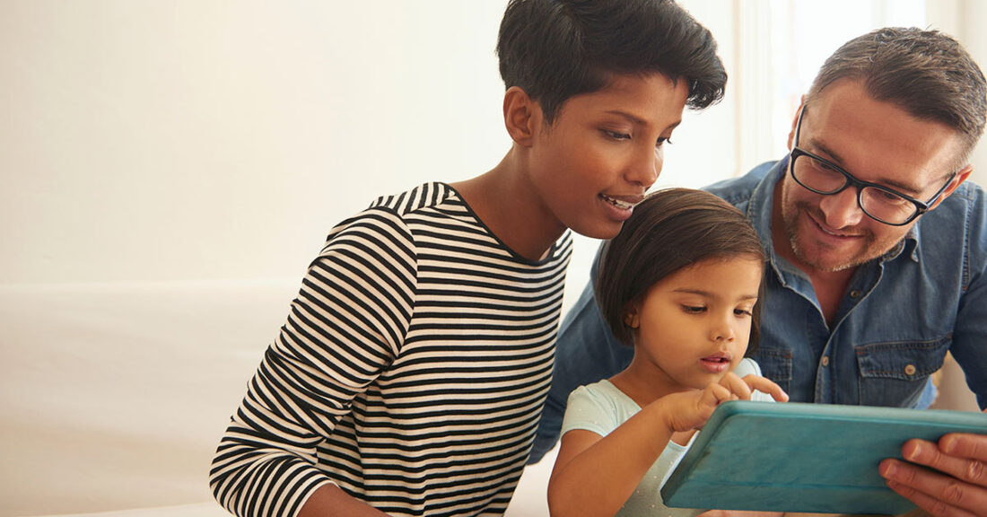 Mother and father look at a tablet with their child