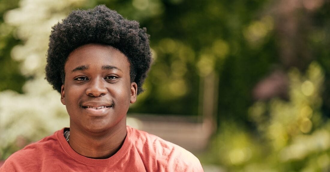 Young black man is similing and looking right at the camera.