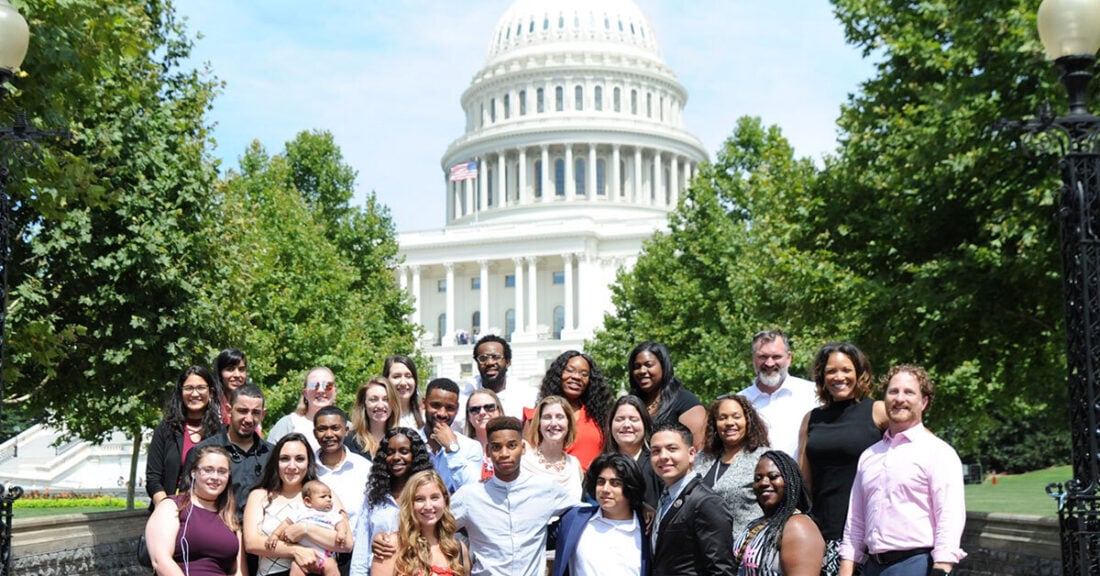 A diverse group of young leaders and adults pose together in front of the U.S. Capitol Building, representing youth engagement and advocacy efforts.