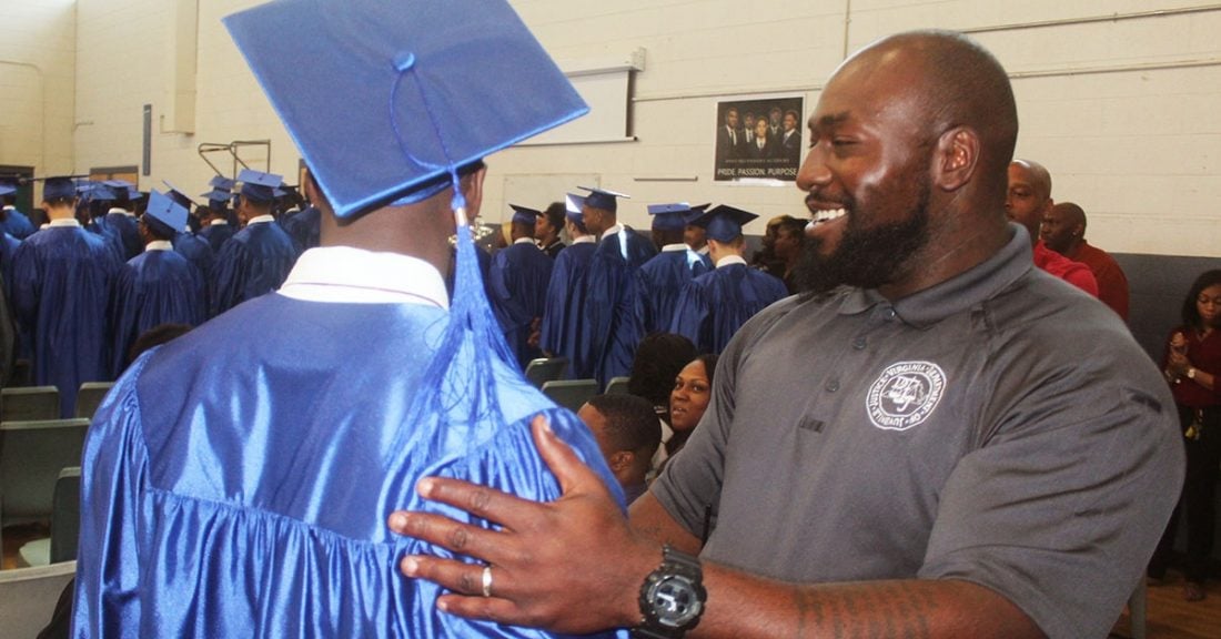Young person at graduation ceremony being congratulated by a man
