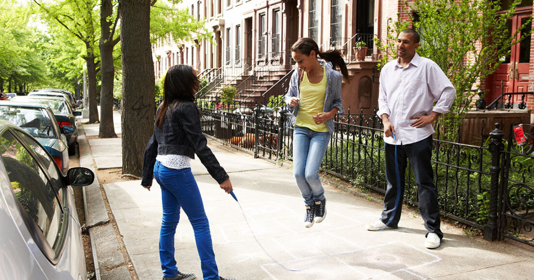 Children and dad playing jump rope in their neighborhood