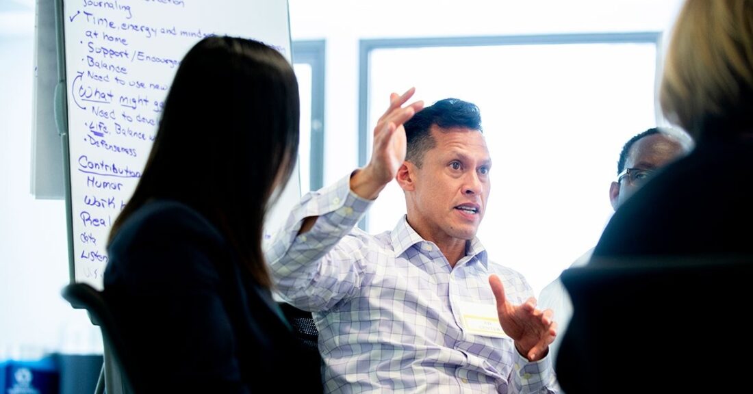 Hispanic male sits in a circle of people and talks