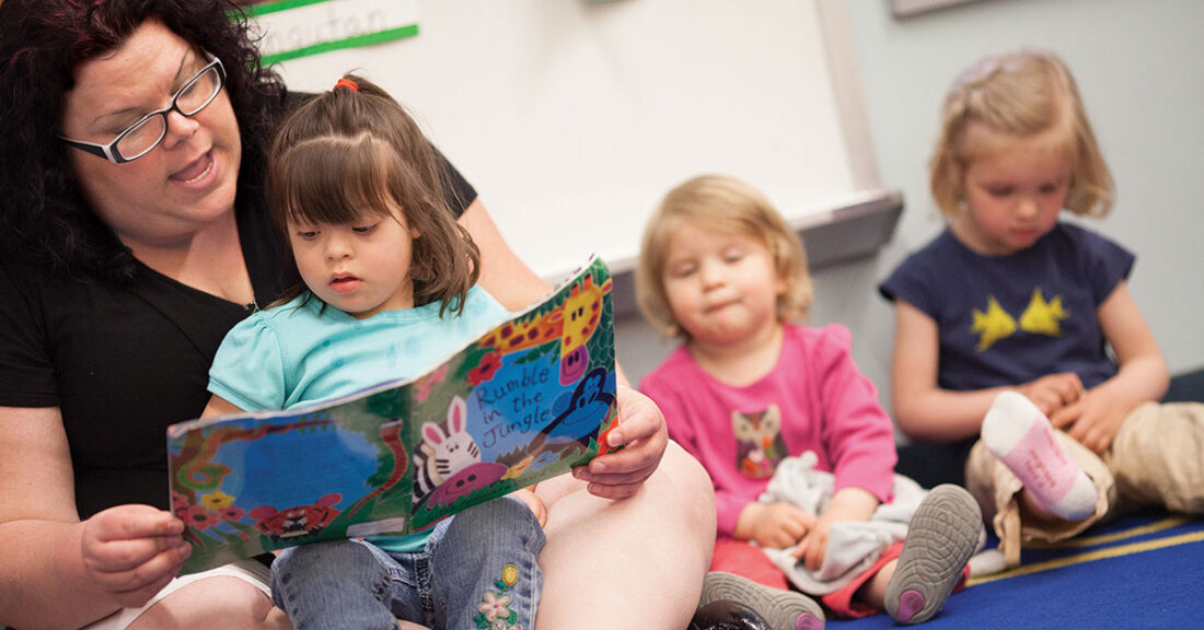 Woman reads to child in a day-care setting.