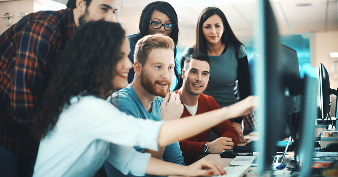 Young people gather around a computer to find innovative solutions through technology.