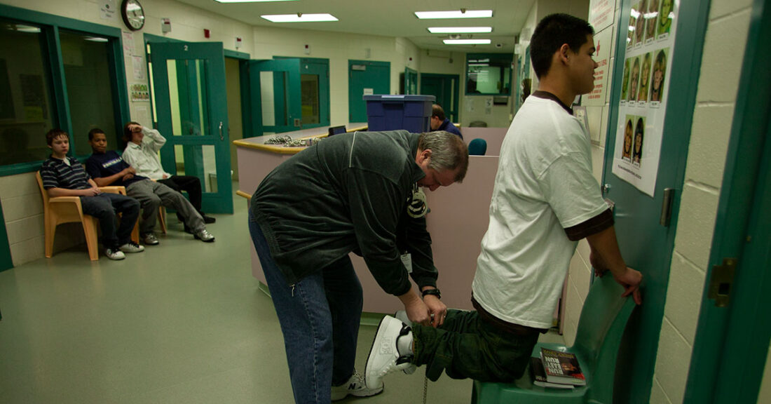 Young person being placed in leg shackles