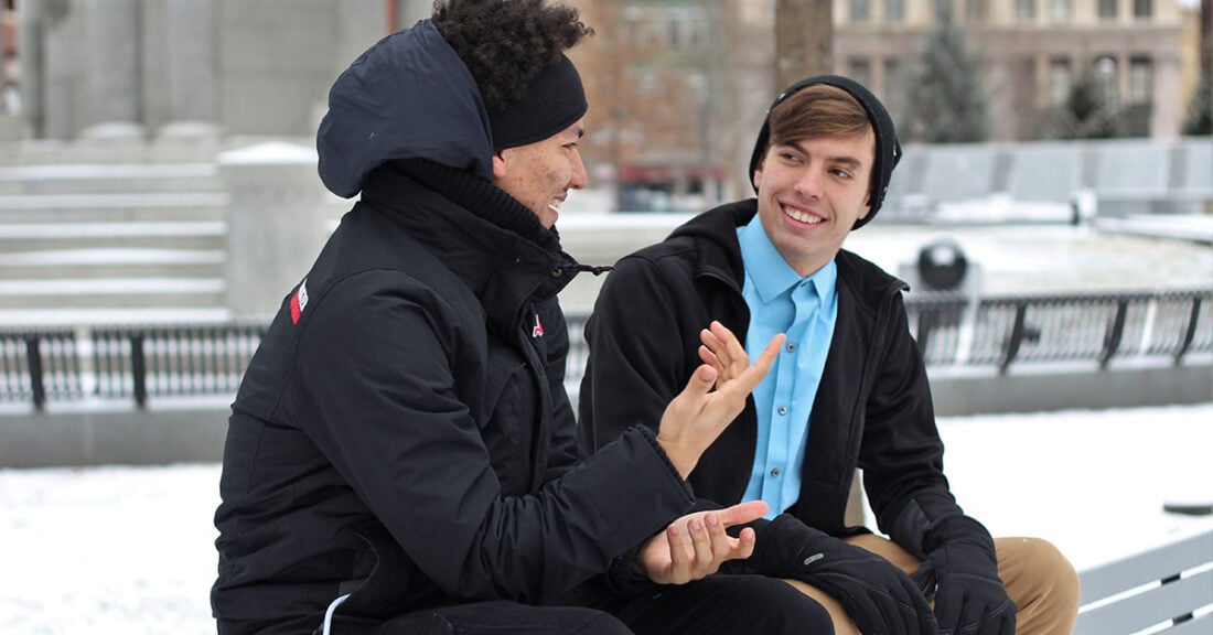 Two young men sitting on a bench in a park