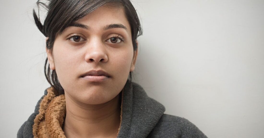 Women photographed in hoodie against a white backdrop