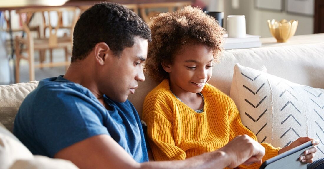 Father sits with daughter on couch