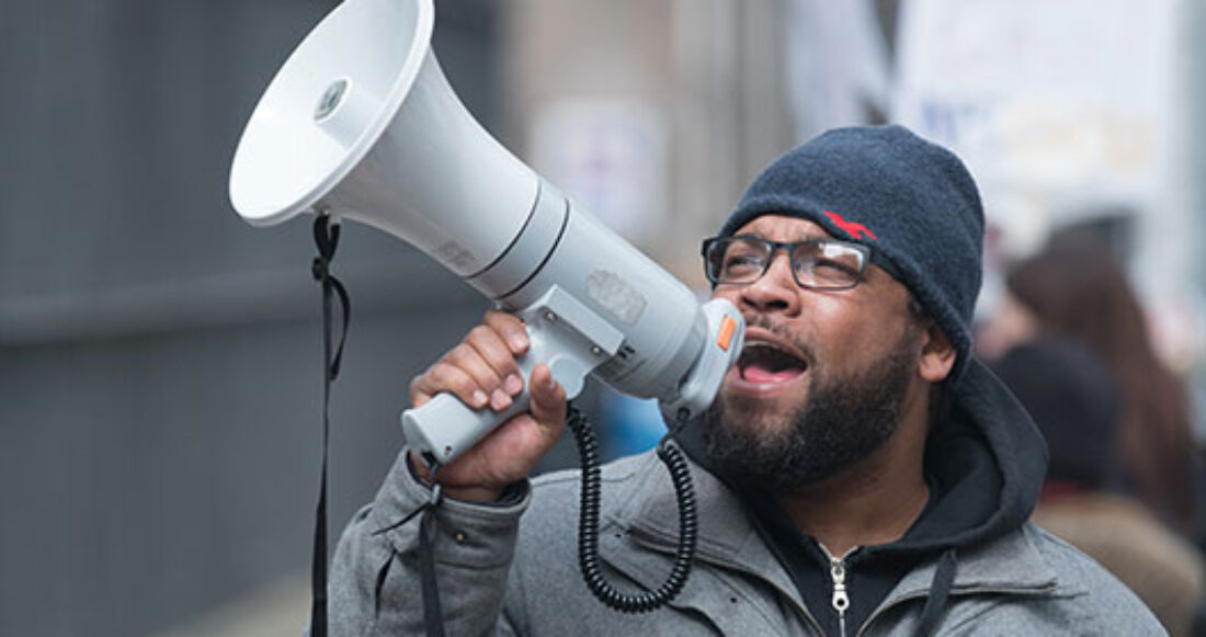 Man at protest speaks into megaphone.