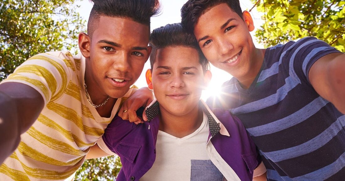 Three teens looking down at camera with sun shining through