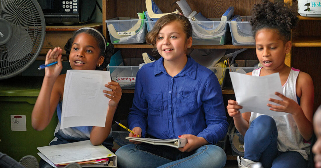 Children in a group setting reading handouts