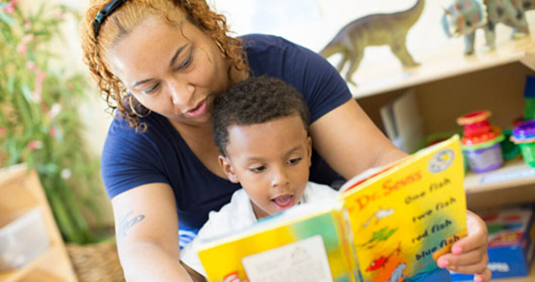 Child care worker and child reading together