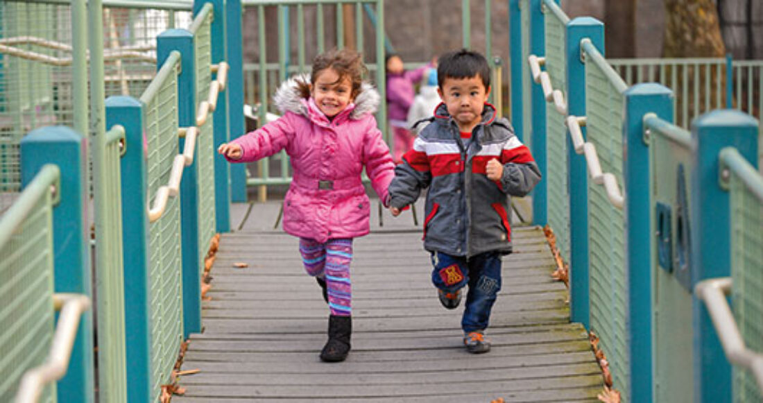 Two children run on a playground