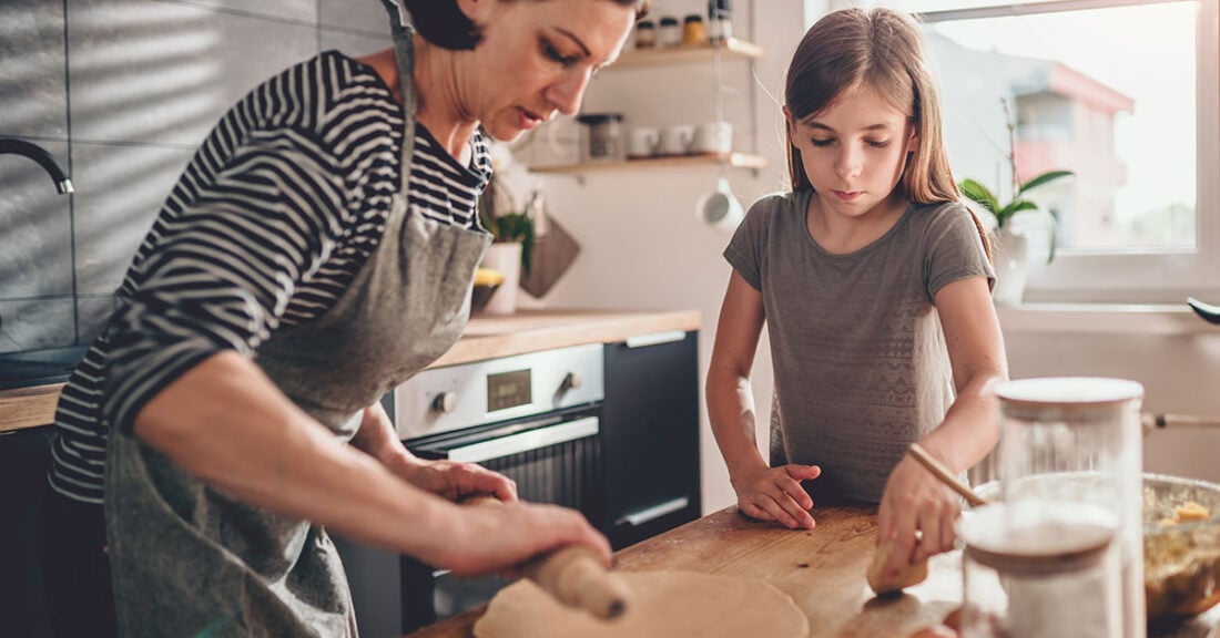 Adult woman cooks with the help of a teen.