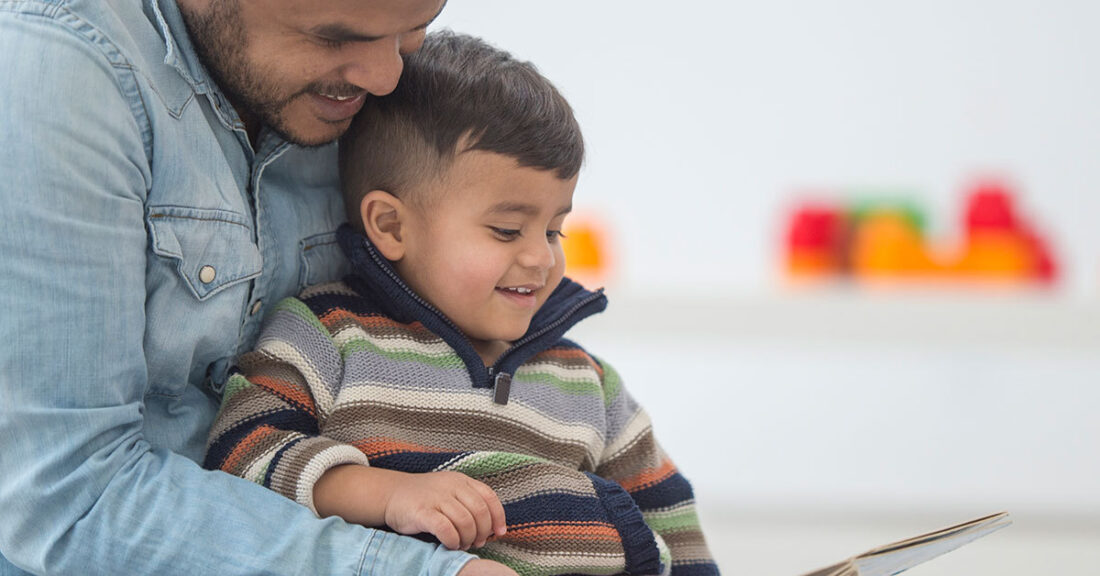 Young dad reads to his toddler.