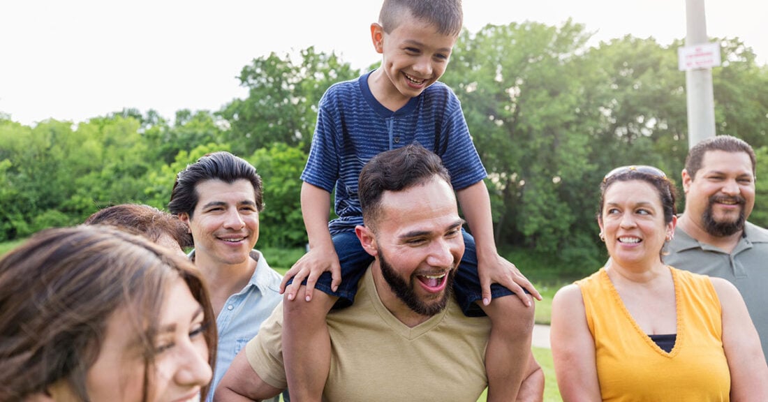 Child on adult's shoulders surrounded by family members