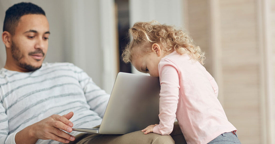 Father with laptop as child looks on