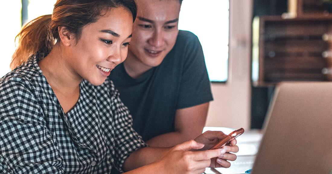 Young couple looks at bills together on the computer