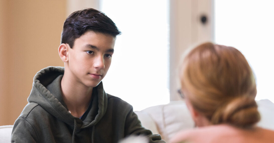 A male youth looks intently at a woman, both are seated.