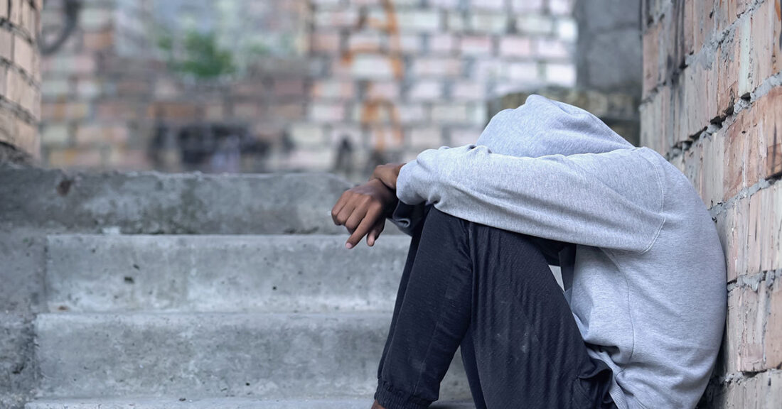 Young person sits on the ground and appears distressed