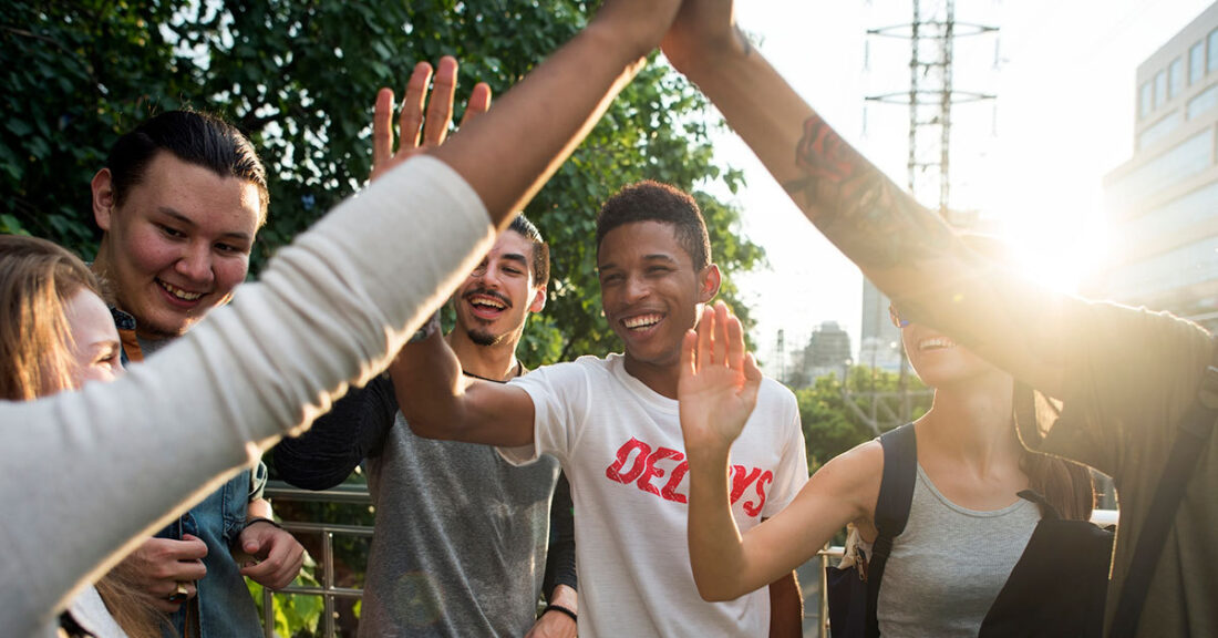 Group of young people giving each other a "high five."