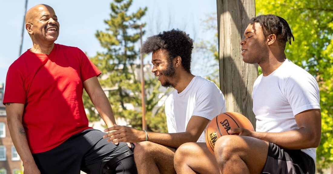 Older Black male talks with two young people outside