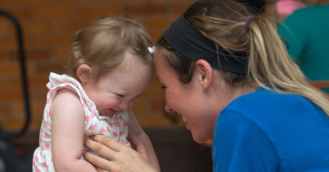 Woman smiling and leaning in, forehead to forehead, with a young toddler girl.