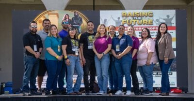 Twelve people from Riverside County's Probation Program stand together, on stage, smiling.