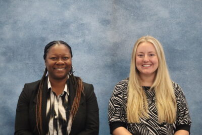 Two women, Tymesha Buckner Dobyes and Maggie Penrose, look straight at the camera, smiling, against a blue background.