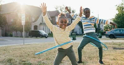 Two young teens (a boy and a girl) play with hoola hoops outside