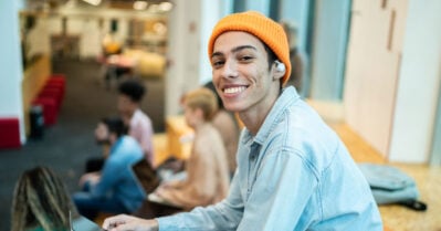 Portrait of a young student man using mobile phone at university.