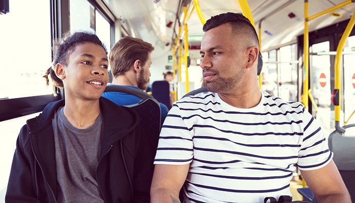 Adult man traveling by bus with his teenage son. Male passengers are commuting by public transport.