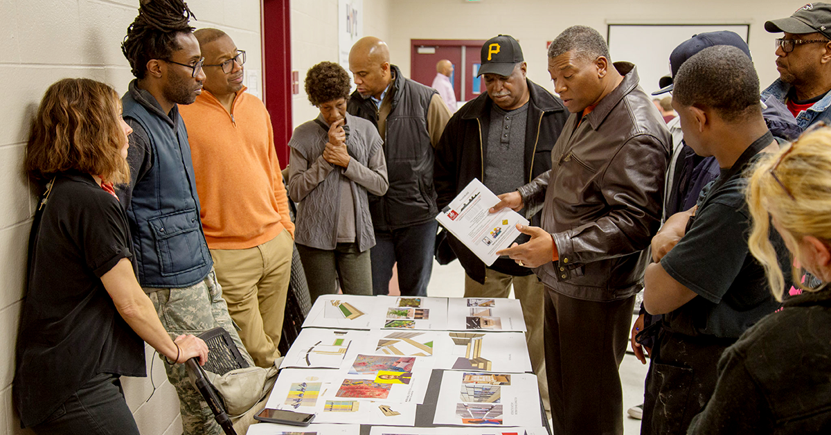 A group of residents stand around a table discussing papers on display.