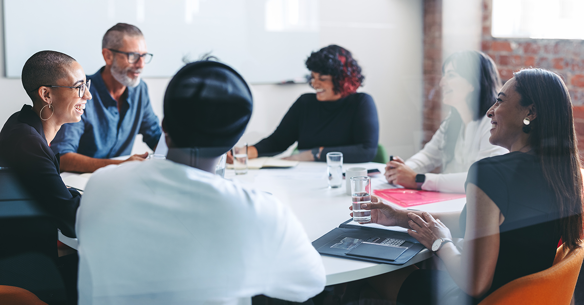 A group of young leaders sit around a conference table having a pleasant discussion